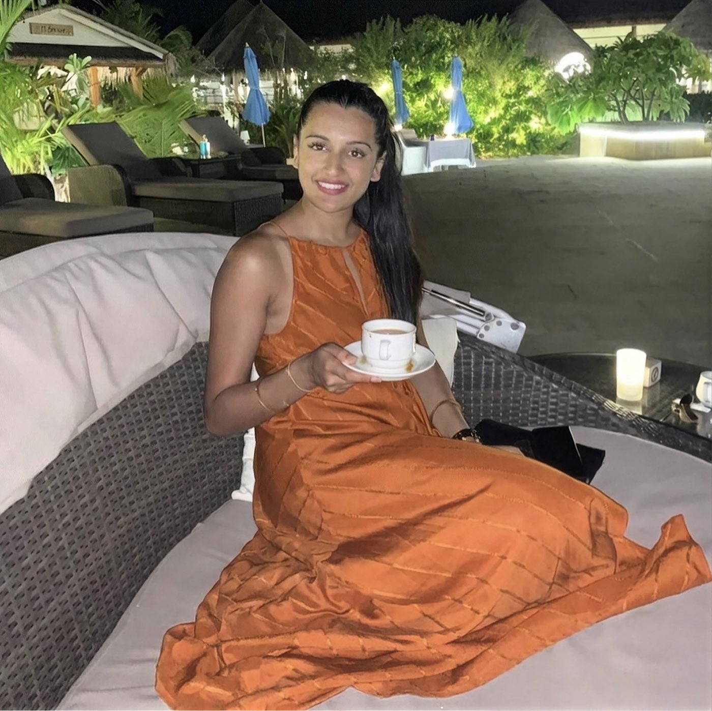 Reena, sitting outdoors in the evening with a cup of tea